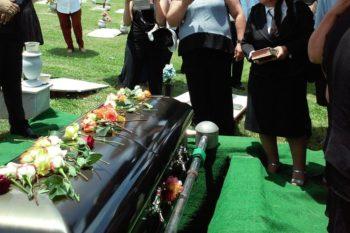 funeral y personas delante de un ataud